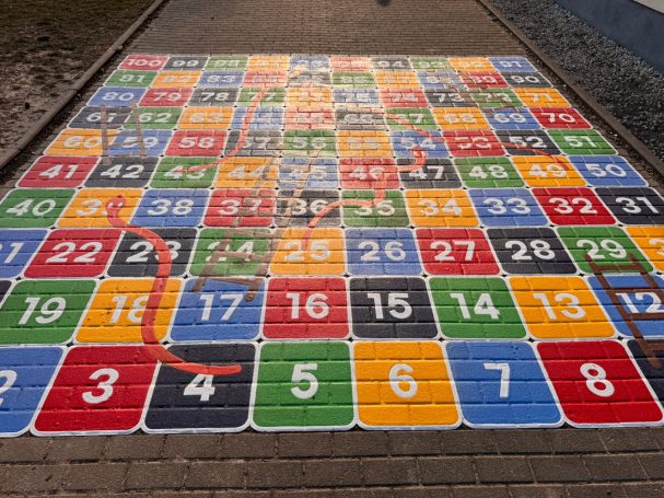 Bunte Zahlenfelder auf grauem Boden, angeordnet in einem Quadratsspiel.